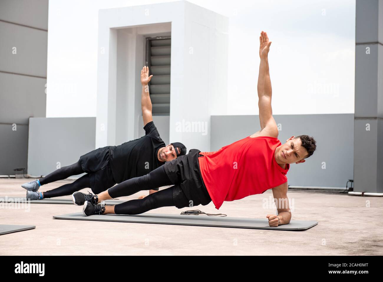 Group of athletic men doing side plank workout exercise outdoors on rooftop floor Stock Photo
