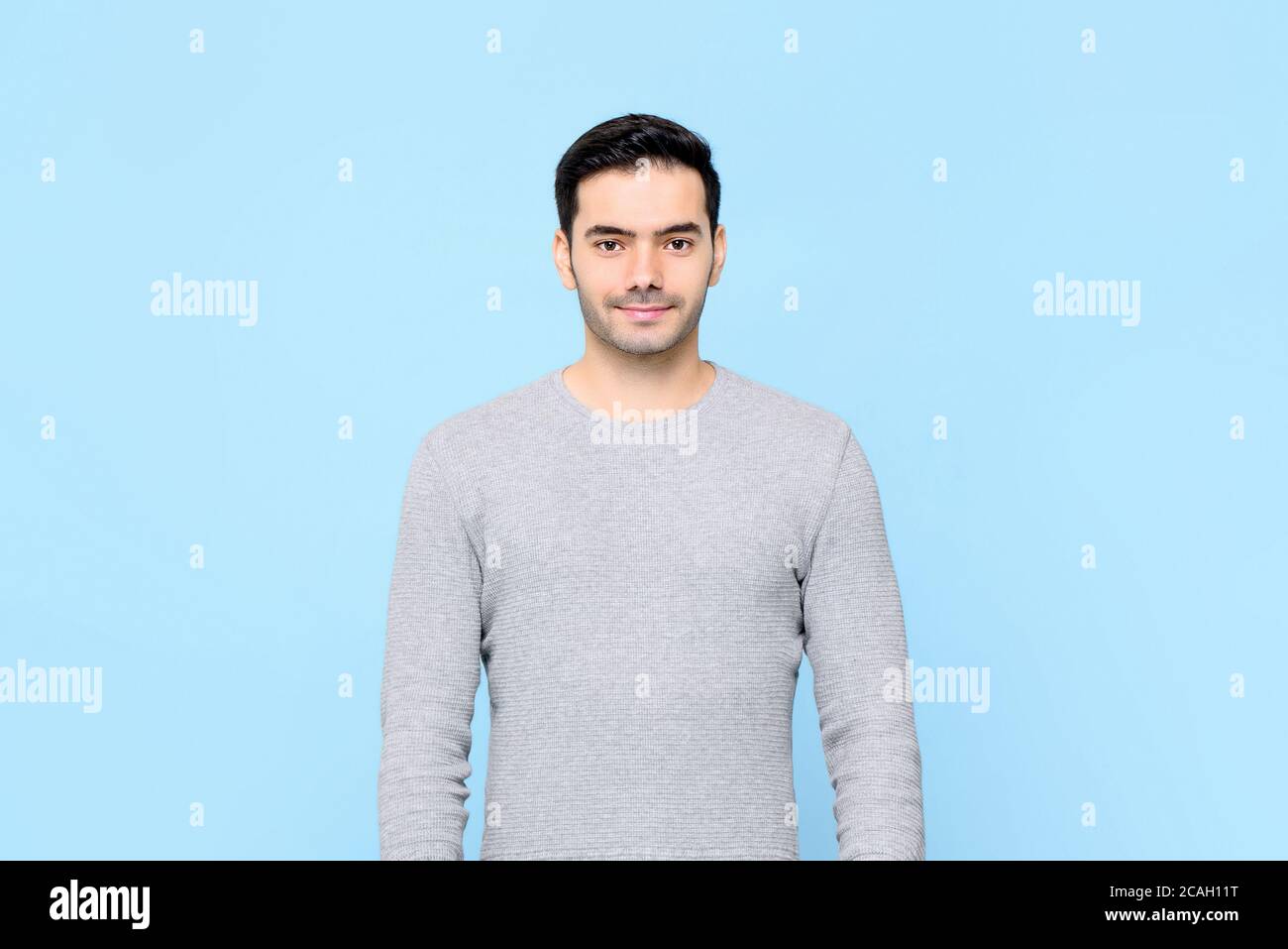 Waist up portrait of young handsome European man in plain gray t-shirt isolated on light blue studio background Stock Photo