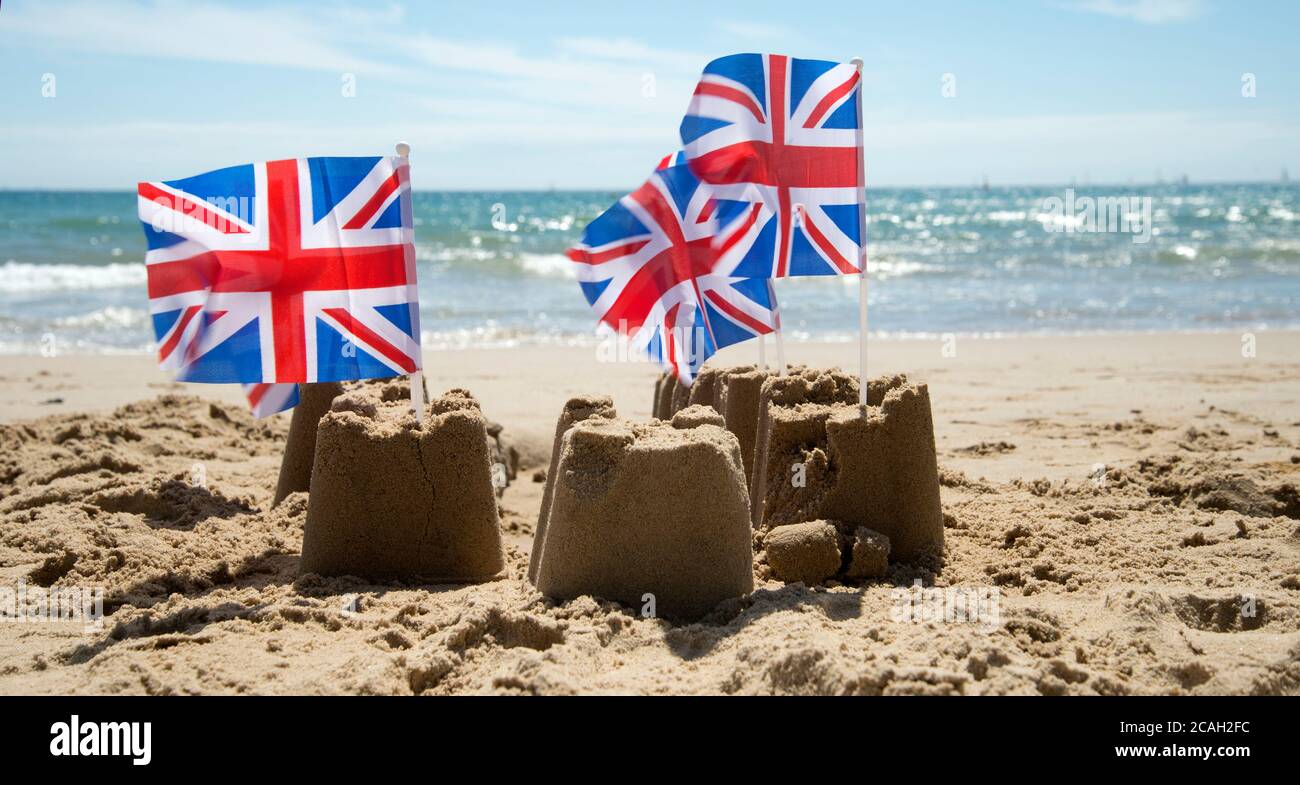 Summer in Dorset. Poole. Crumbling sandcastles with Union Jacks Stock Photo