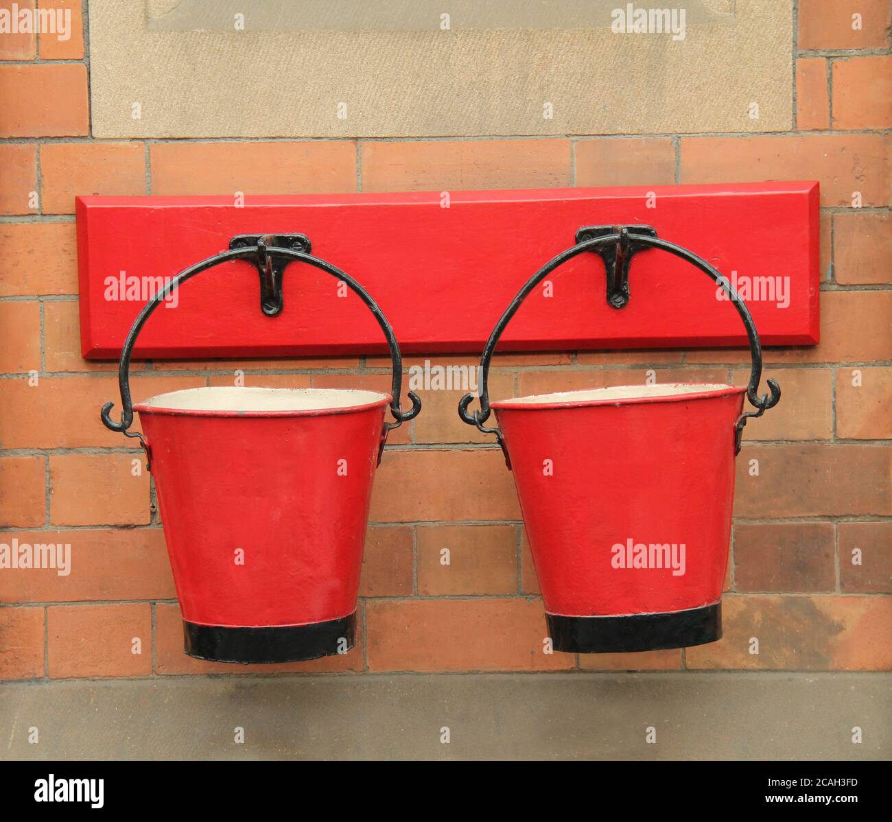 Two Red Vintage Fire Buckets Hanging on a Brick Wall. Stock Photo