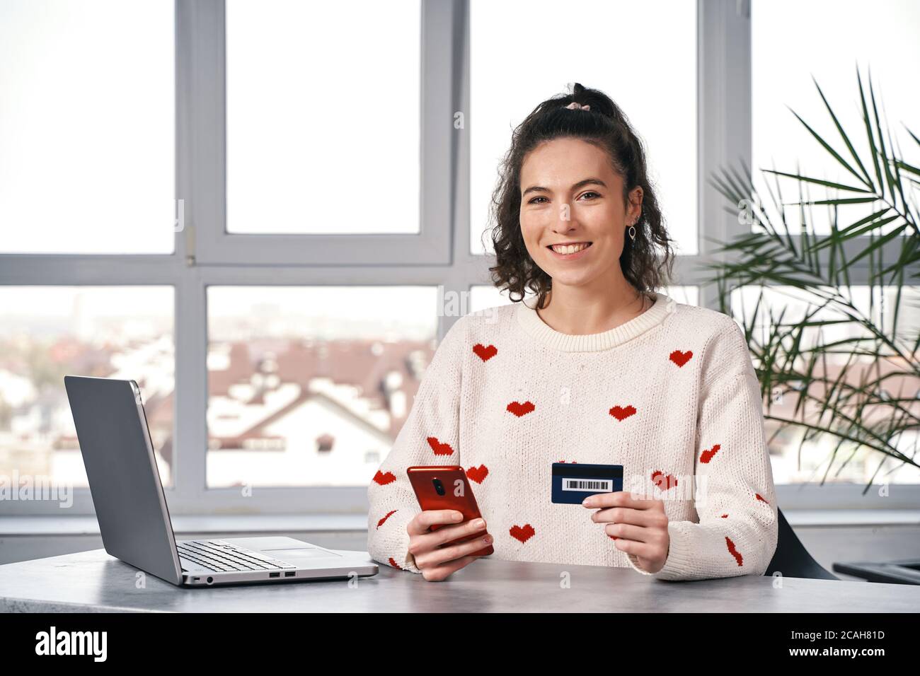 Happy smiling woman with red phone and credit card buying in the internet. Shopping online Stock Photo