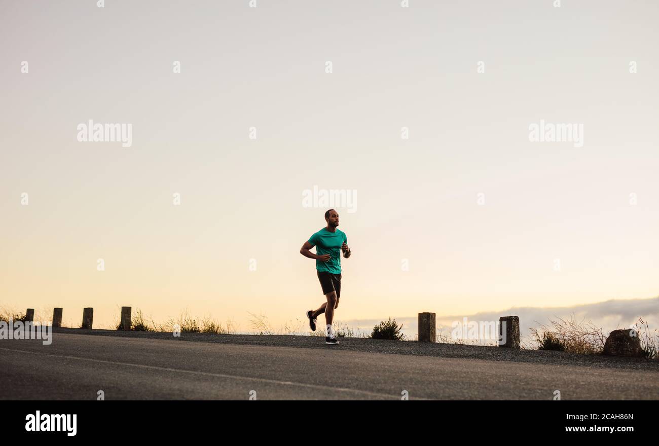 Athlete running on empty road in the morning. fitness runner on a morning run on the highway. Stock Photo