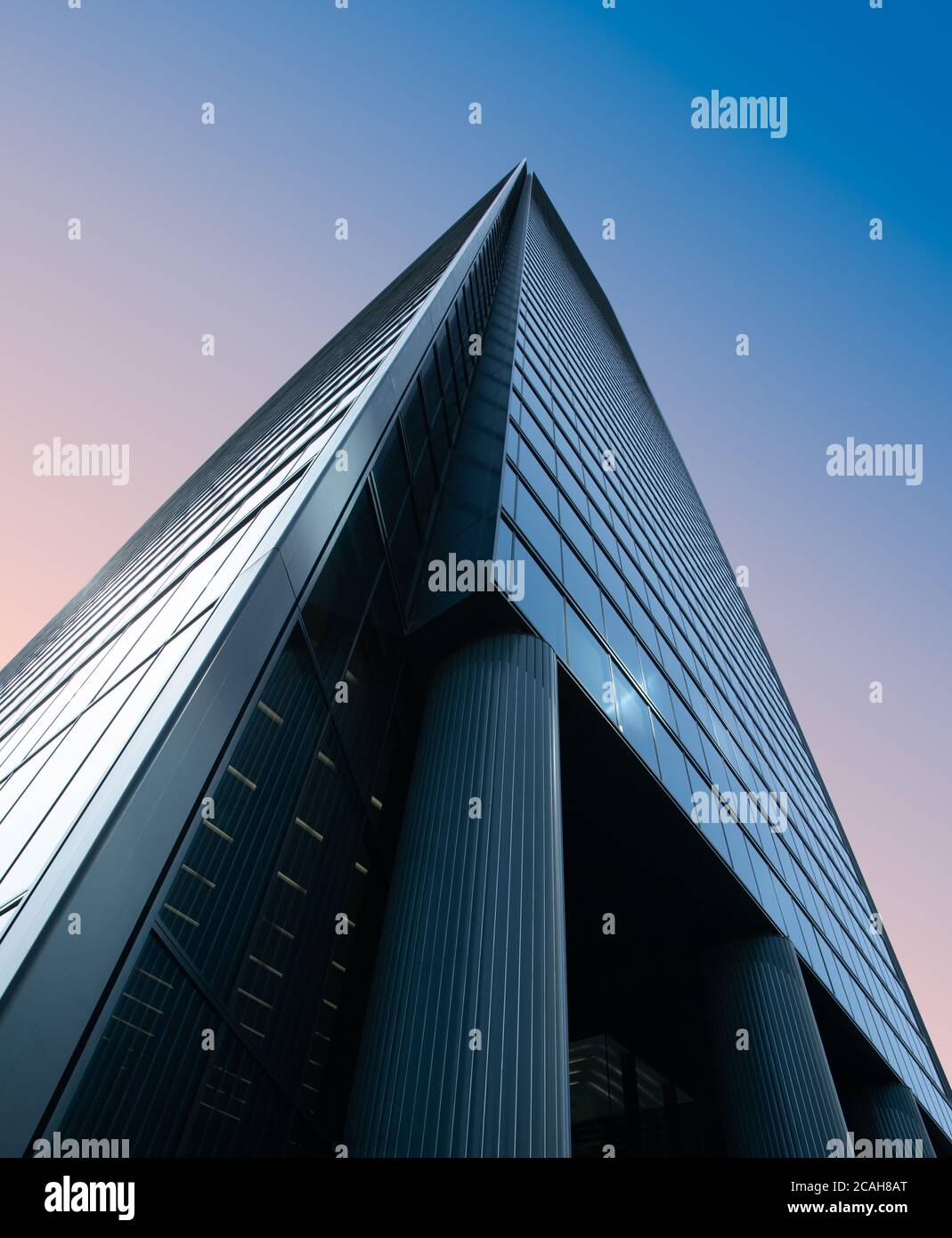 Low angle view of a business office building against pink and blue sky Stock Photo