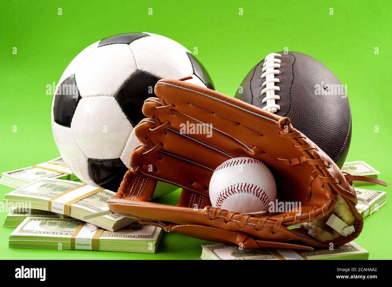 Winning bet on sporting event, money in sport and sports betting conceptual idea with baseball glove, football, soccer ball and wad of cash isolated o Stock Photo
