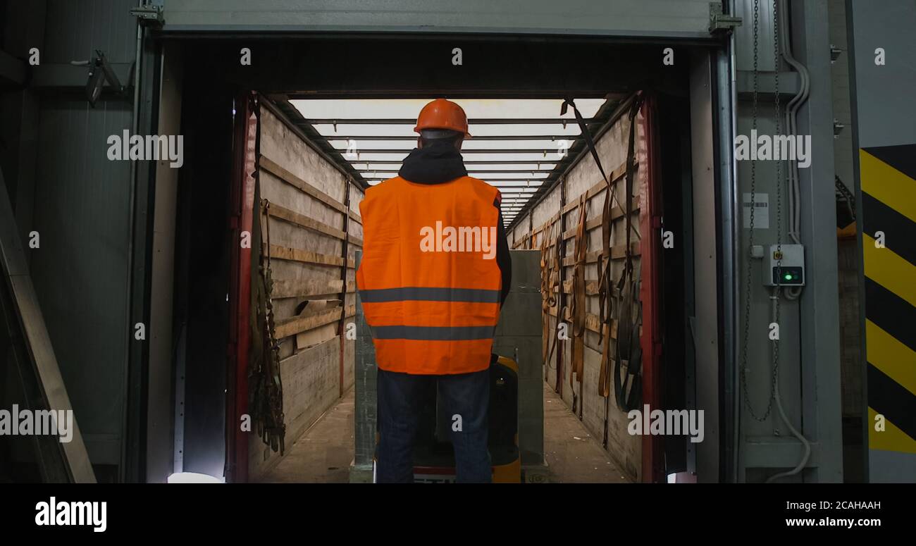 warehouse worker driver in uniform loading cardboard boxes by forklift ...