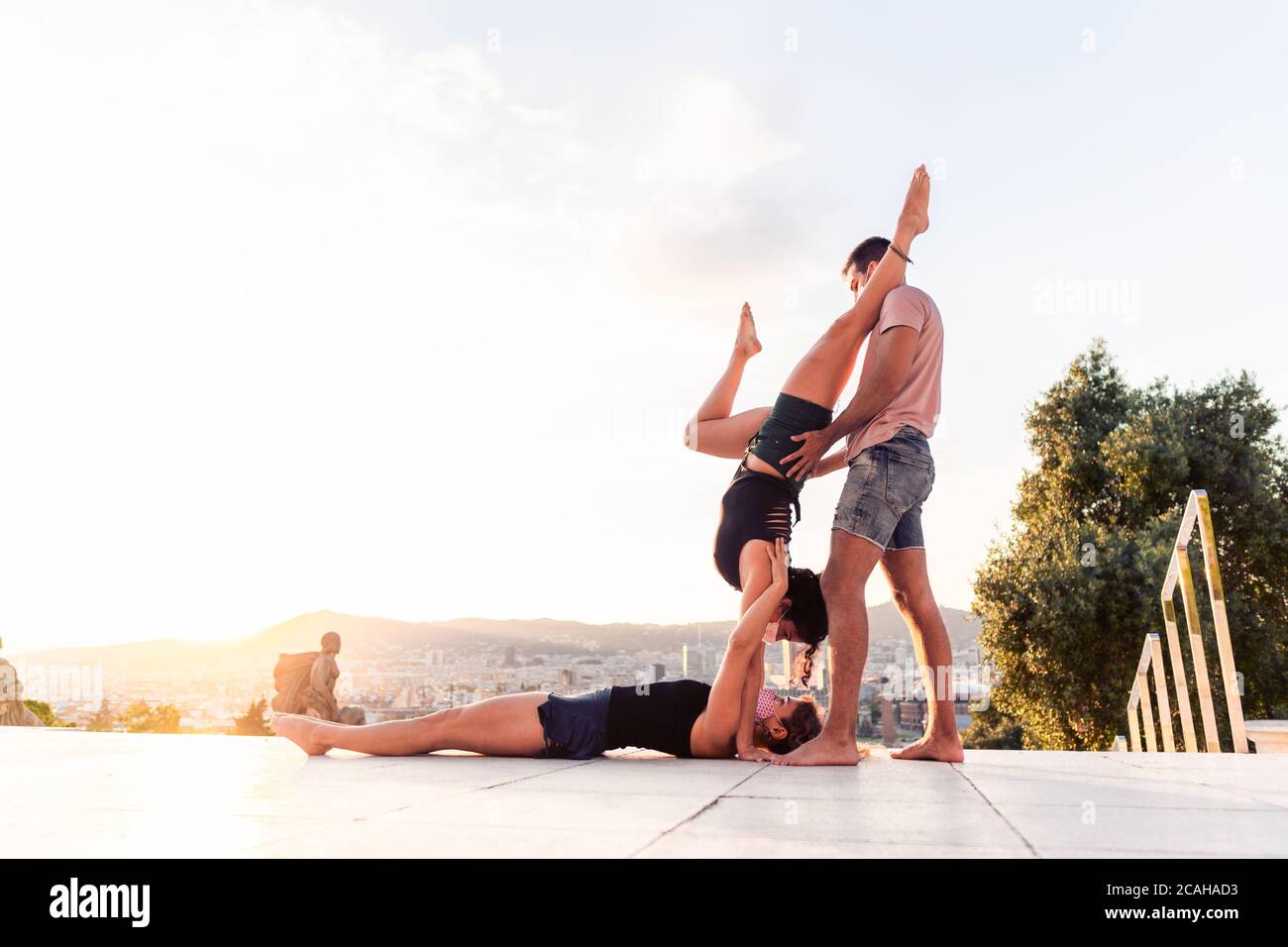 Beautiful man and two women doing acroyoga in the city Stock Photo
