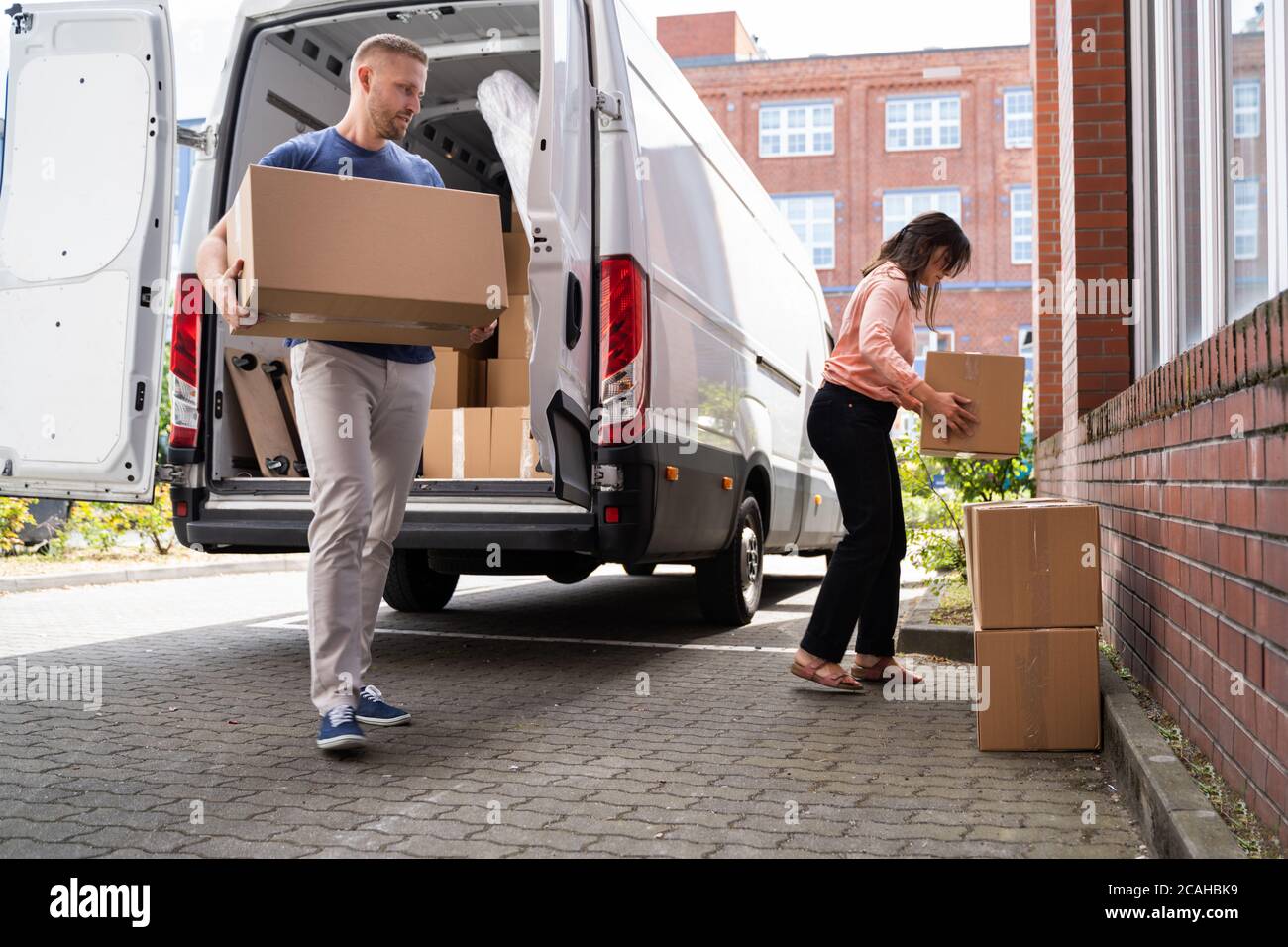 Couple Moving Boxes From Van Or Truck Together Outdoors Stock Photo