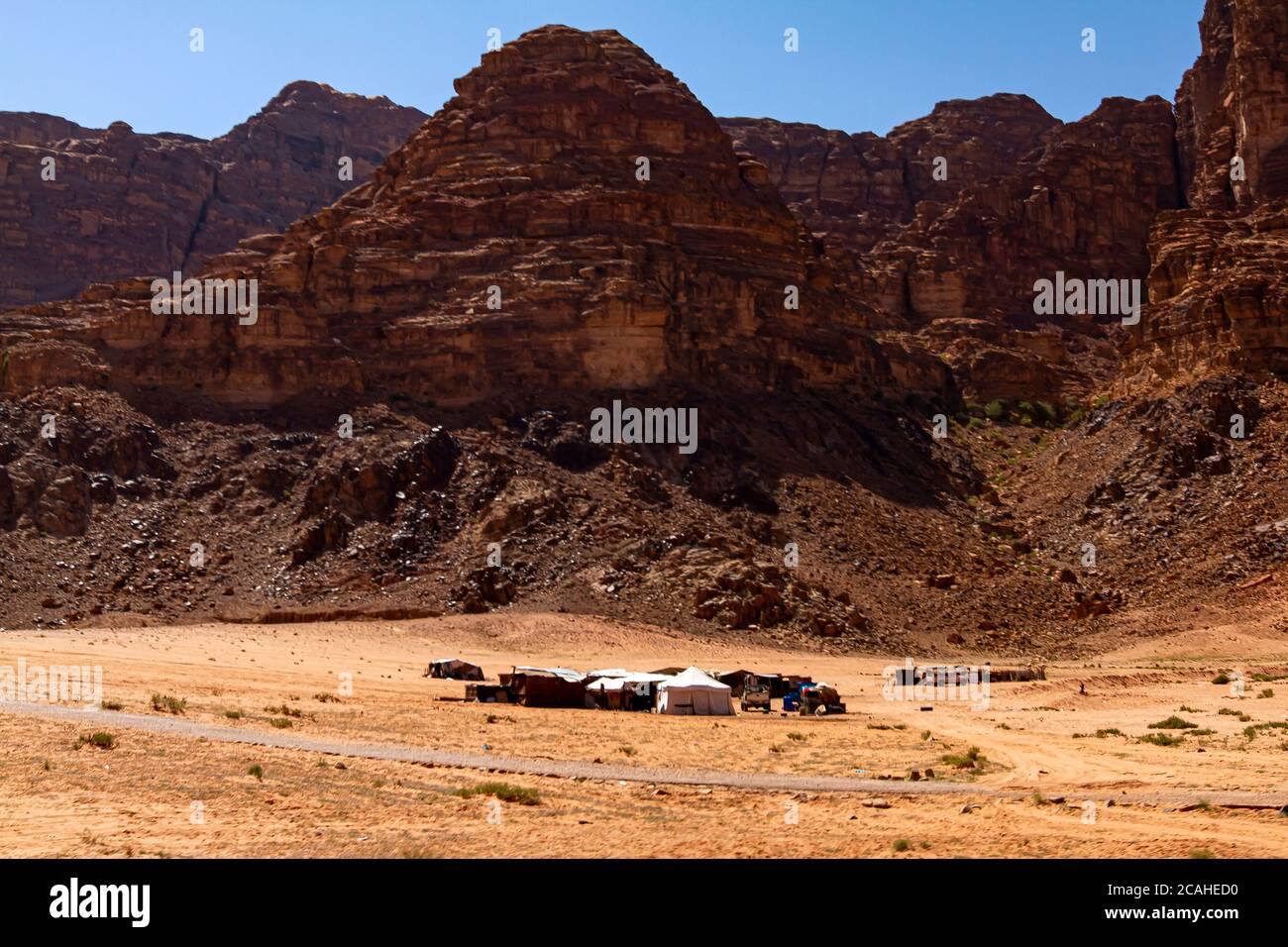 A small group of Bedouin tents established at a remote location on sands of Wadi Rum Desert. Image features tents, shades and off road vehicles on the Stock Photo