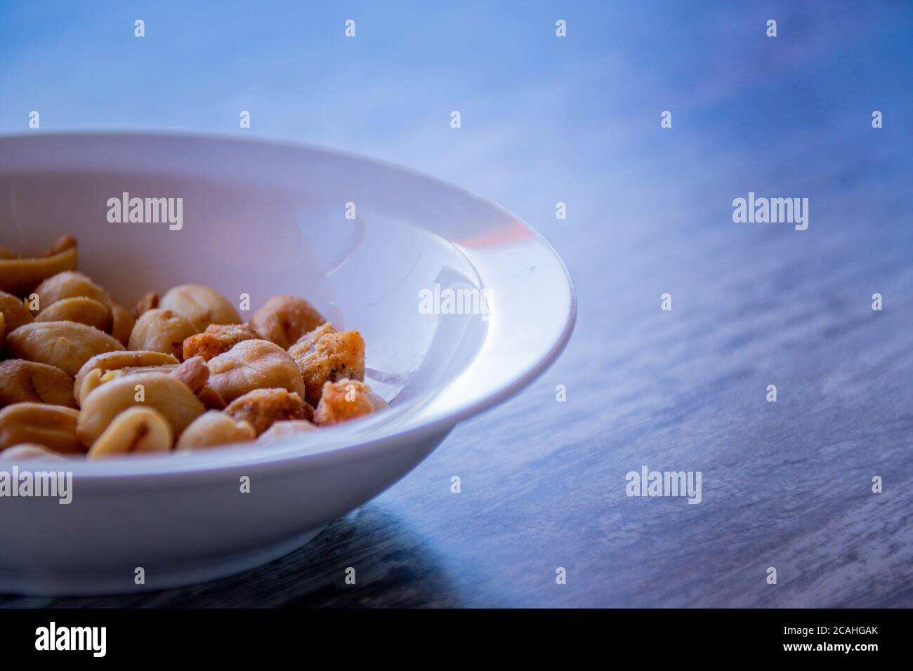 Bowl of peanuts on a woodden table Stock Photo
