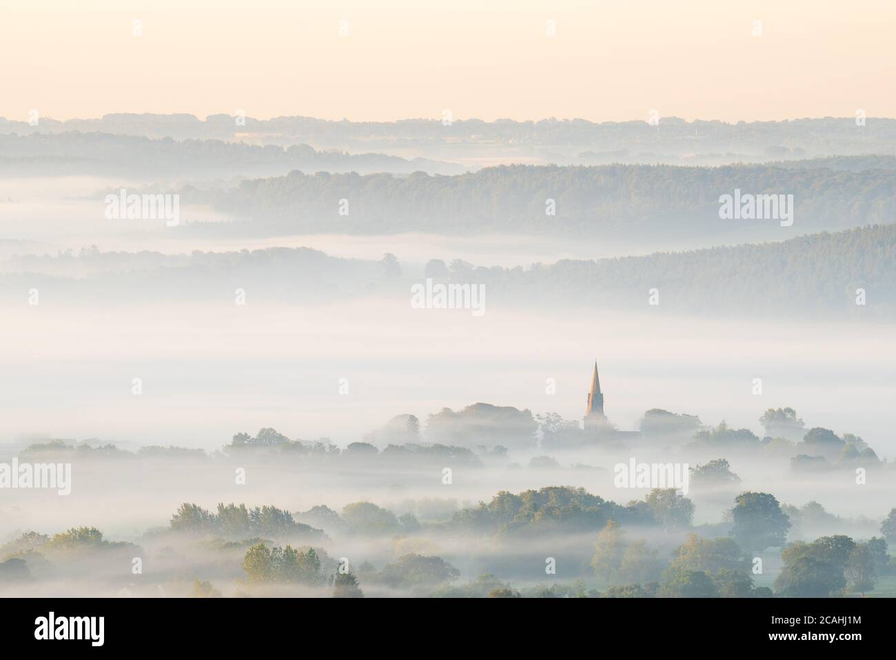 The steeple of St Barnabas Church in Weeton catches the early morning light on a beautiful foggy summer morning in Lower Wharfedale. Stock Photo