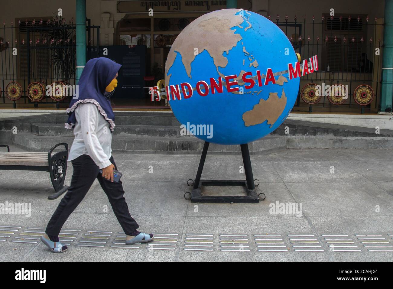 Yogyakarta, YOGYAKARTA SPECIAL REGION, INDONESIA. 7th Aug, 2020. A woman wearing a mask to protect herself from the corona virus outbreak crosses the globe that reads 75 years of Indonesian Independence in Yogyakarta, Indonesia. Friday, 7 August 2020. Minister of Finance of Indonesia, Sri Mulyani Indrawati said, the Corona Virus pandemic has hit all economic sectors. At present, only economic activity that switches to digital online can survive the challenges. Credit: Slamet Riyadi/ZUMA Wire/Alamy Live News Stock Photo