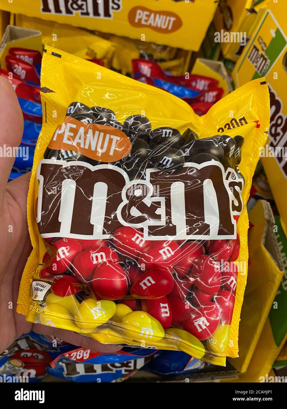 Viersen, Germany - July 9. 2020: View on hand holding yellow M&M chocolates bag in german supermarket Stock Photo