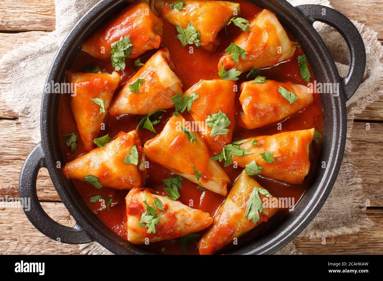 Stuffed cabbage leaves with minced meat and rice in tomato sauce close-up in a bowl on the table. Horizontal top view from above Stock Photo
