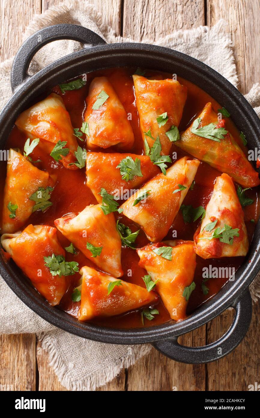 cabbage rolls with meat and rice with tomato sauce and parsley close-up in a bowl on the table. Vertical top view from above Stock Photo