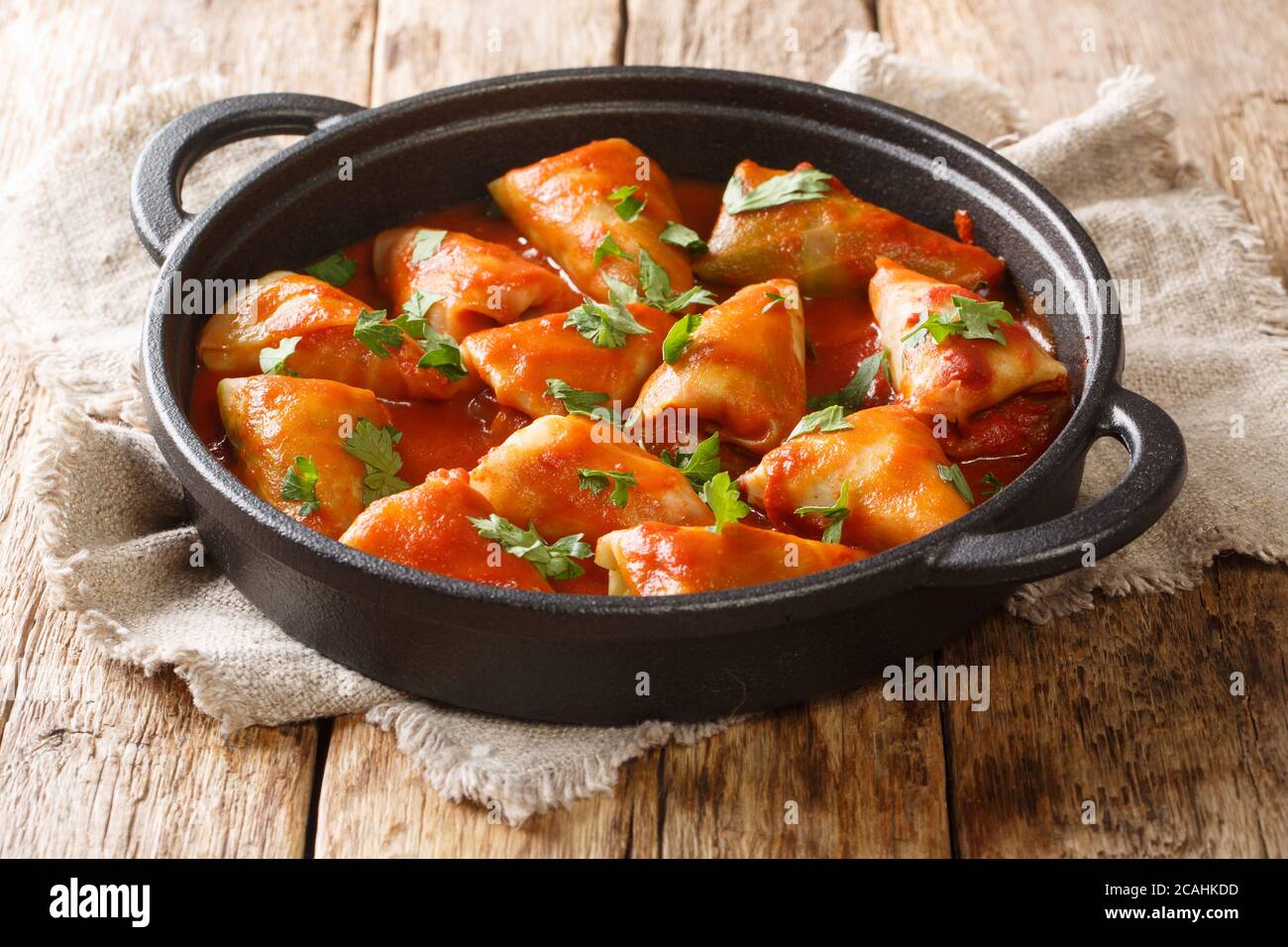 Traditional stuffed cabbage with minced meat and rice, served in a tomato sauce close-up in a bowl on the table. Horizontal Stock Photo