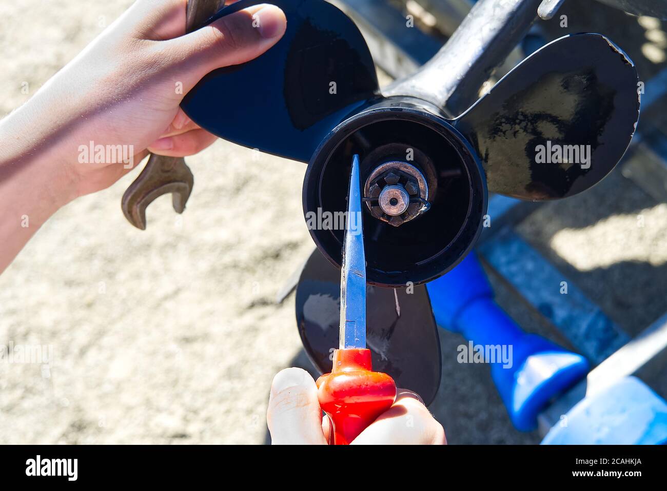 man changing propeller on outboard motor. Repairing outboard motor for boat, replacing screw