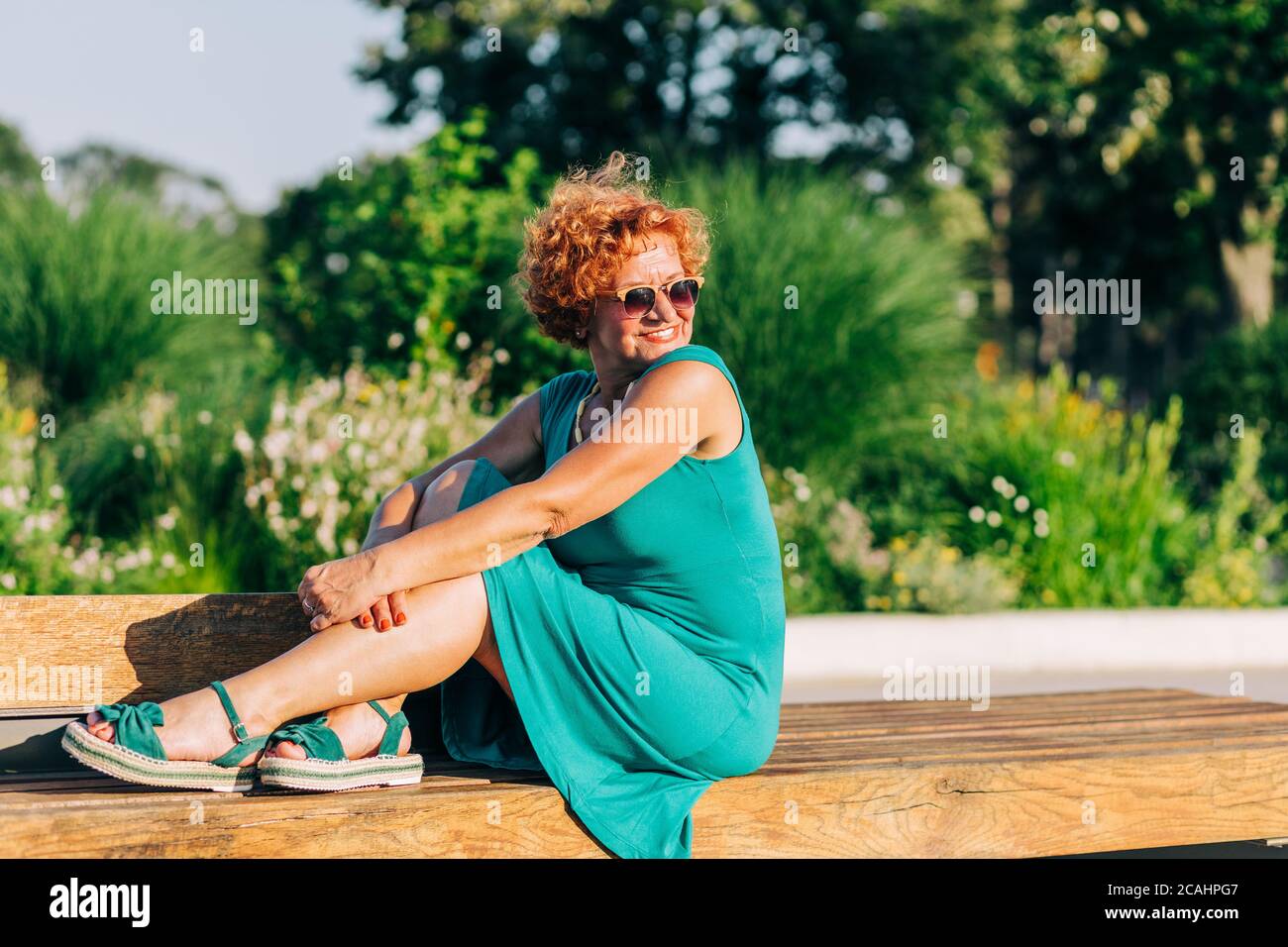 Mature woman sitting on the bench in the park in summertime Stock Photo ...