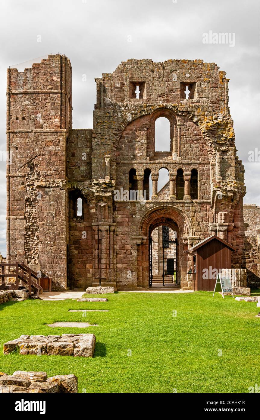 The remains of foundations in the nave of the priory church and the imposing fortified Romanesque style front entrance with its tower and arrow loops Stock Photo