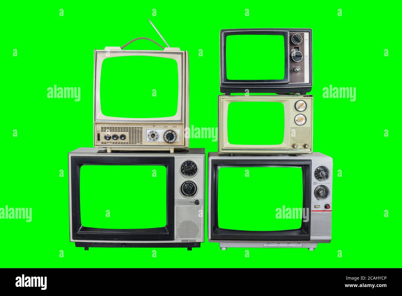 Five vintage televisions on old wood table with green screens and backgrounds. Stock Photo