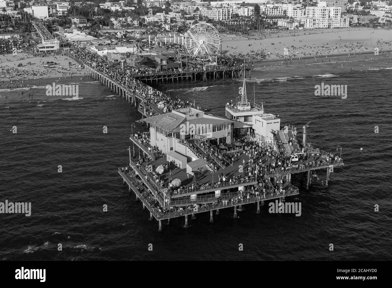 Black and white aerial view of crowded Santa Monica Pier and beach near Los Angeles on the Southern California coast. Stock Photo