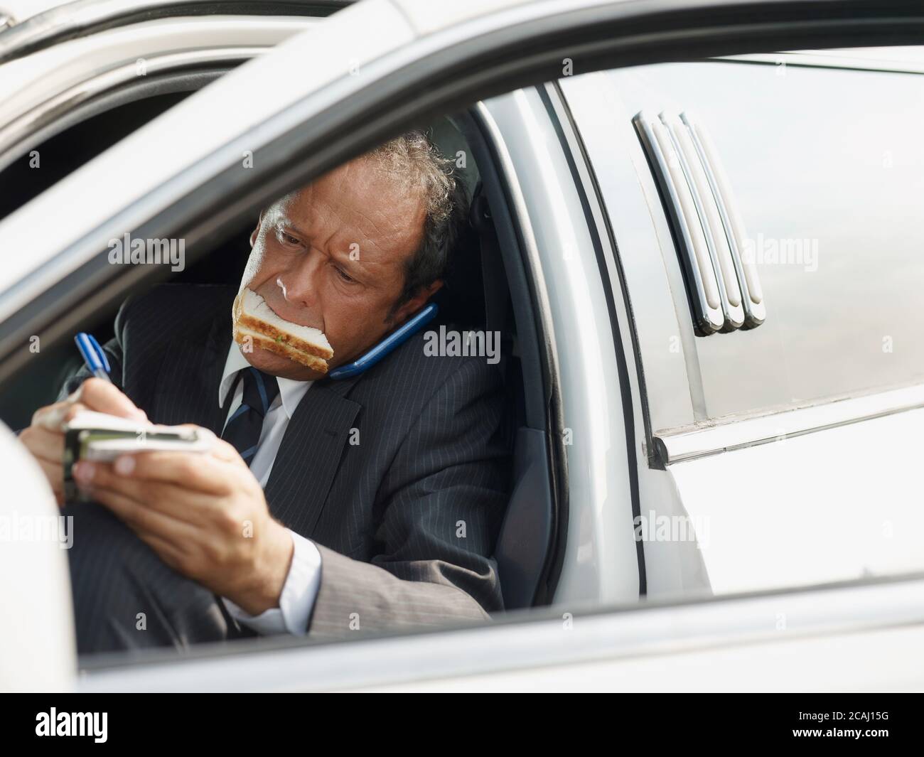Driver Of White Limousine Eating Lunch Inside Car Stock Photo