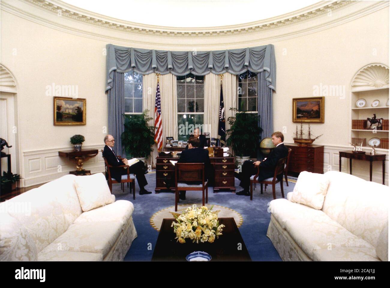 In this file photo, Washington, DC - August 9, 1990 -- United States President George W. Bush meets with national security advisors in the Oval Office at the White House in Washington, DC on August 9, 1990 to discuss the situation in the Persian Gulf and Middle East. National Security Advisor Brent Scowcroft is at far left, President Bush is at center facing camera, Vice President Dan Quayle is at far right, and White House Chief of Staff John Sununu is at center with his back to the camera. Credit: White House via CNP | usage worldwide Stock Photo
