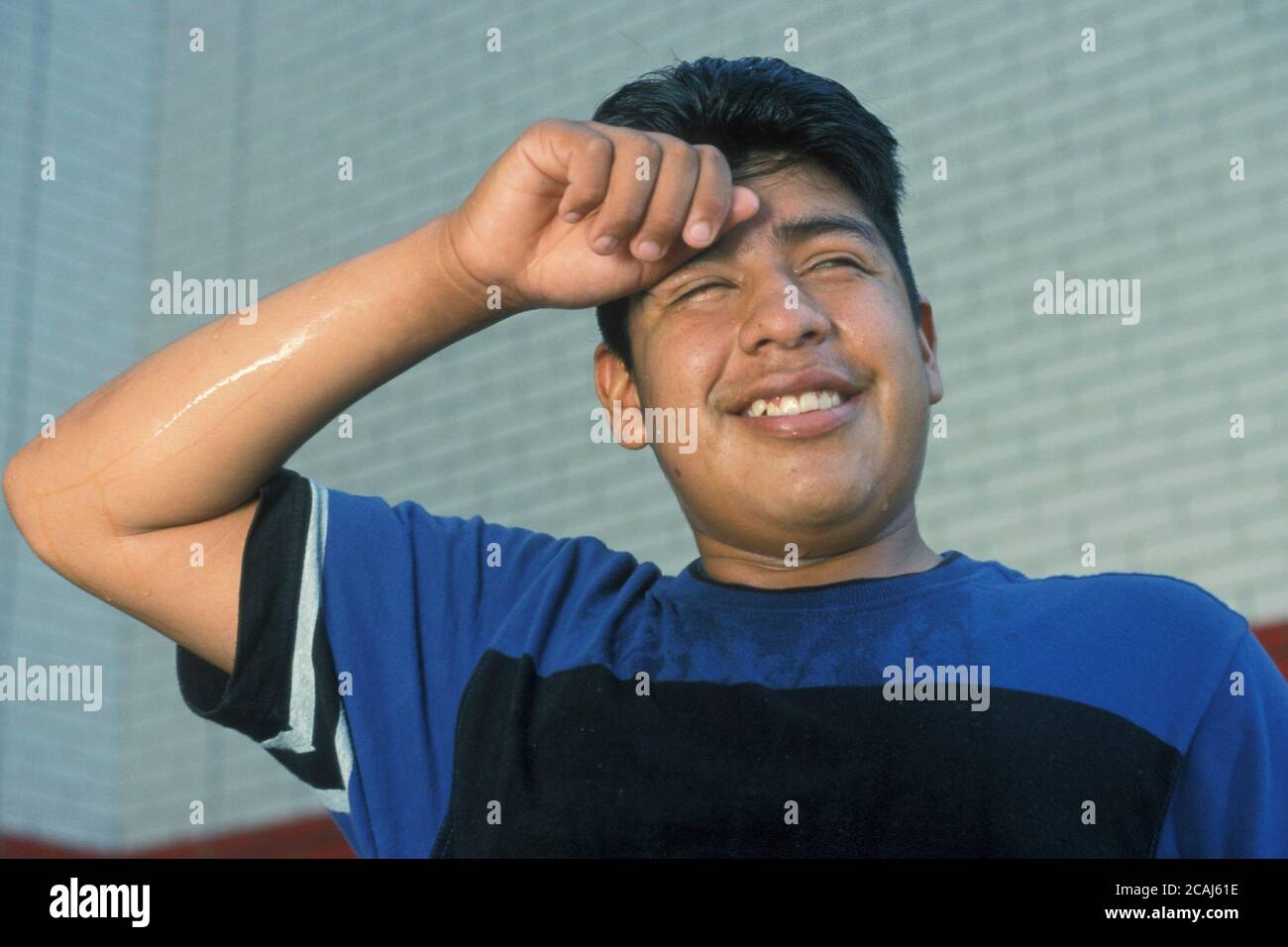 Young Hispanic teenage boy sweating after exercising during high school