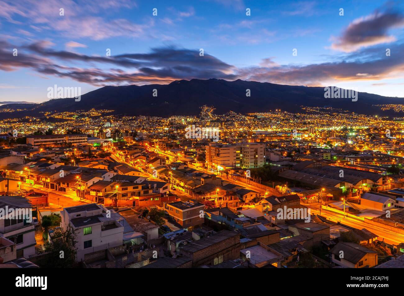 The skyline of Quito at sunset with night lights with the Pichincha volcano, Ecuador. Stock Photo