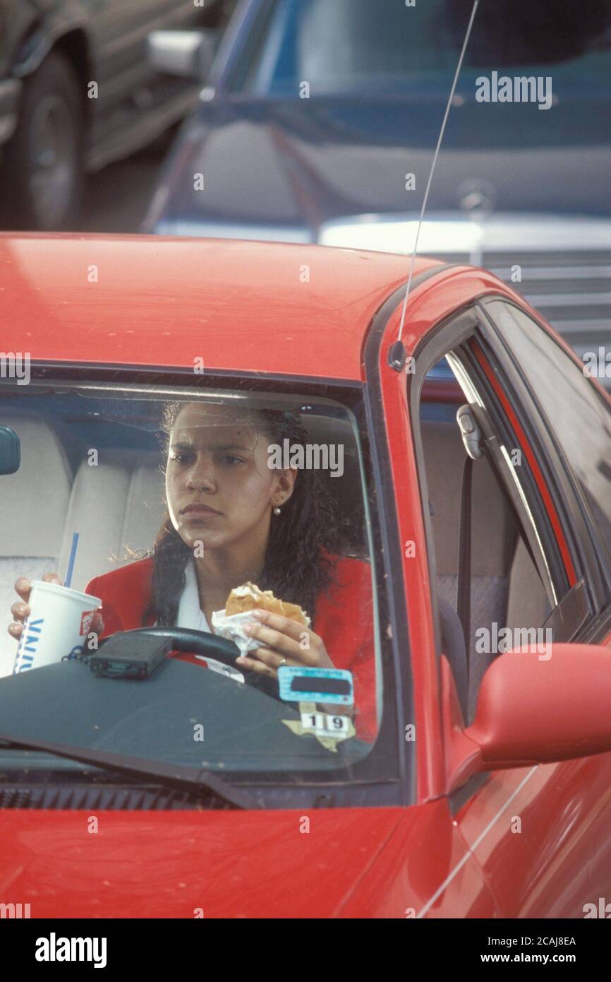 Austin Texas USA Hispanic female driver eating and drinking while driving in morning rushhour