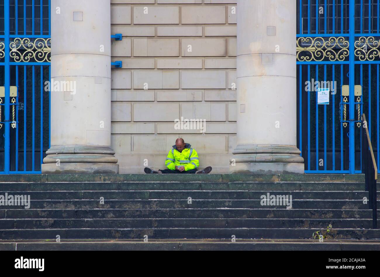 8 July 2020 A man in a hi- iz jacket sitting on the steps of the imposing Sheffield City Hall entertainment centre in Sheffield City England. The hall Stock Photo
