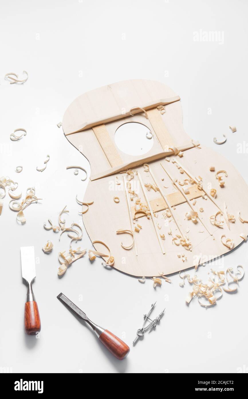 Sound top of guitar under construction with chisels and wood chips