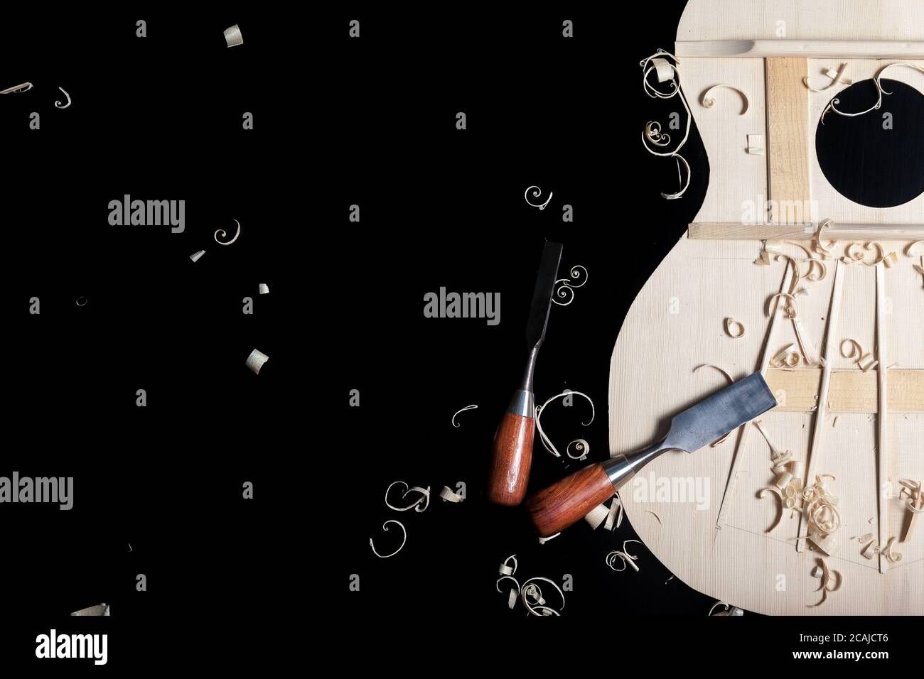 Sound top of guitar under construction with chisels and wood chips