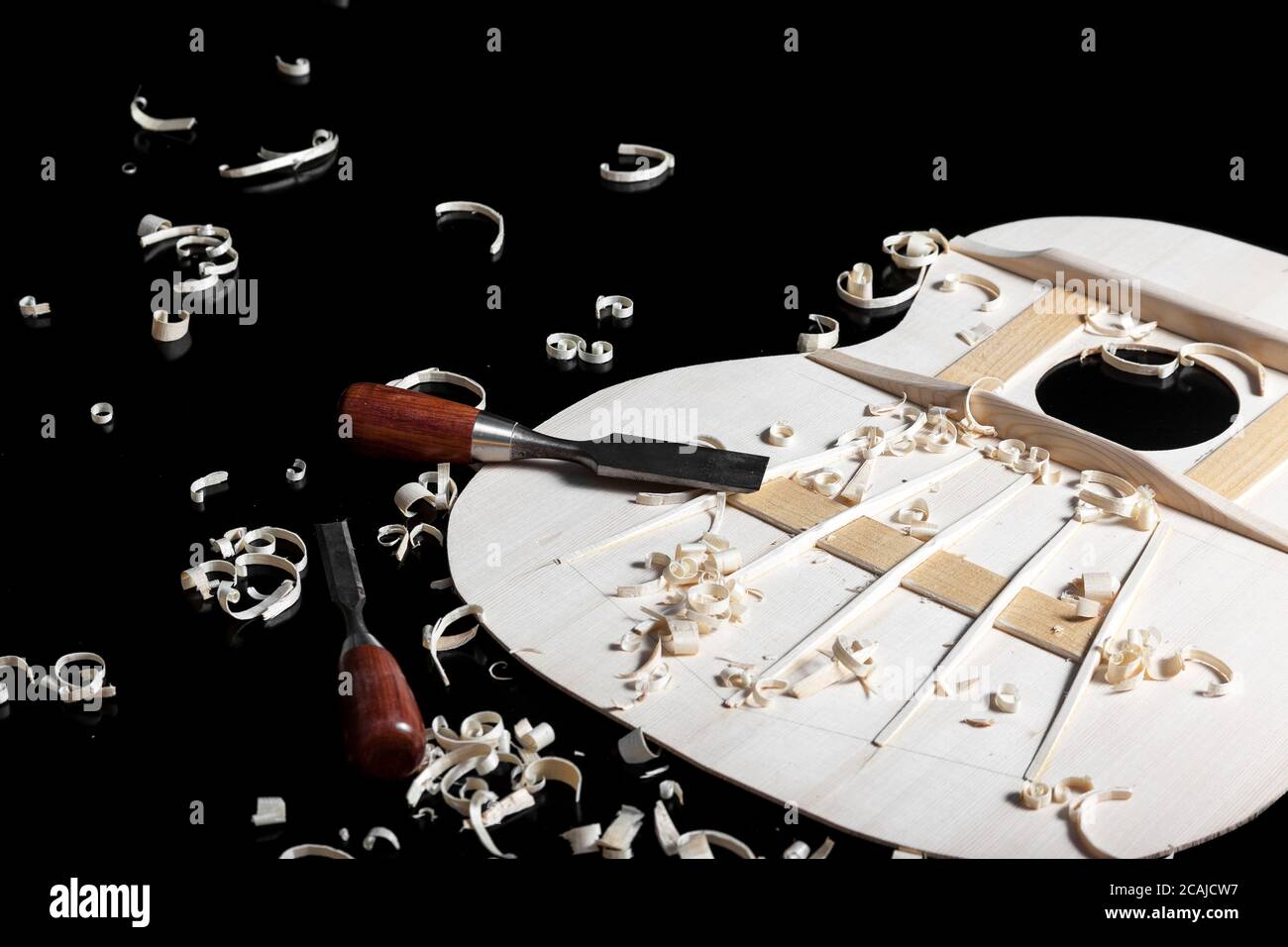 Sound top of guitar under construction with chisels and wood chips