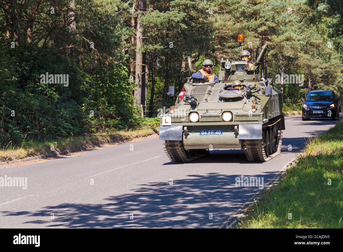 Spartan FV103 armoured vehicle with L plate learner driver, driving along road at Bovington, Dorset UK in August, Armoured Vehicle Driving Assessments Stock Photo