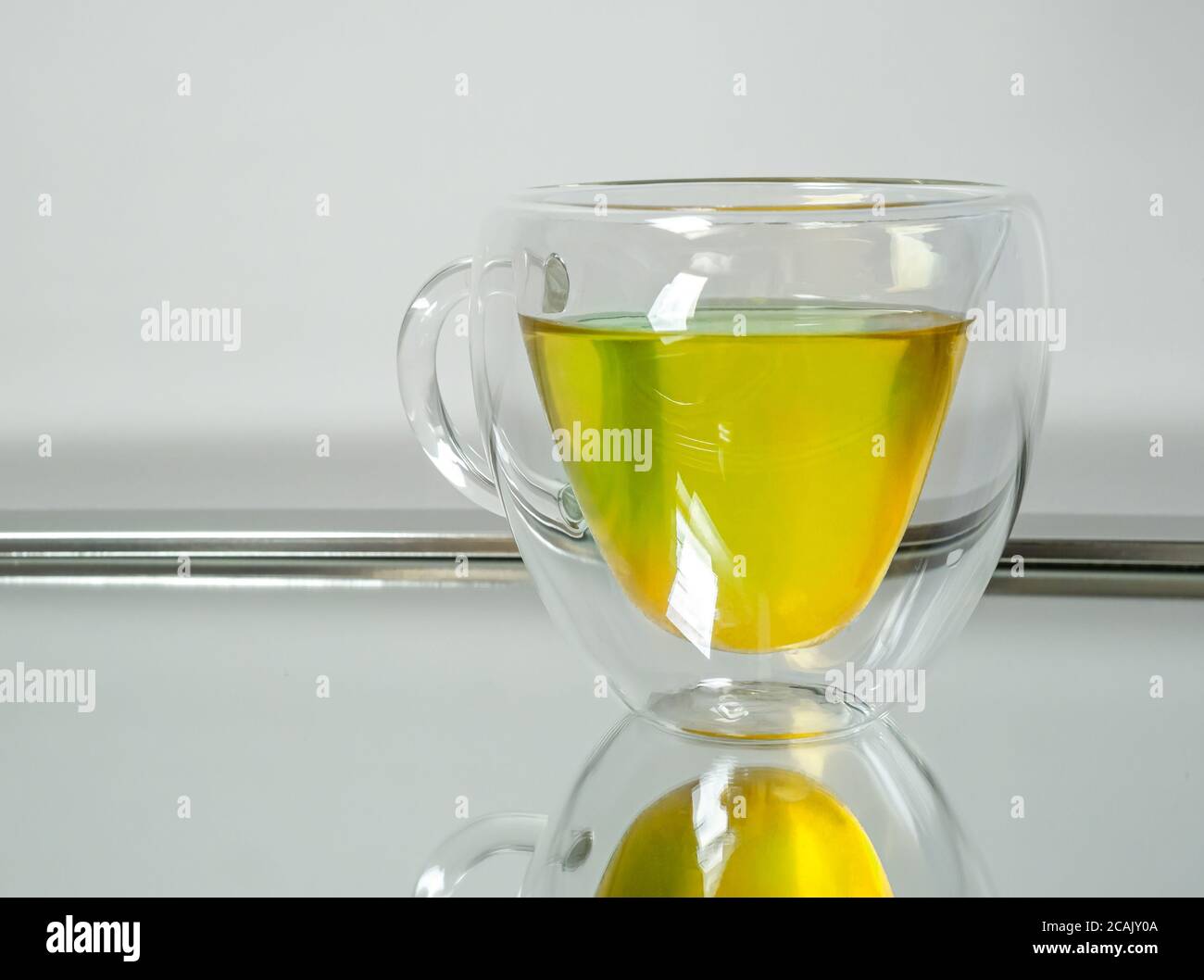 A glass teapot of hot herbal tea reflected on a mirror Stock Photo