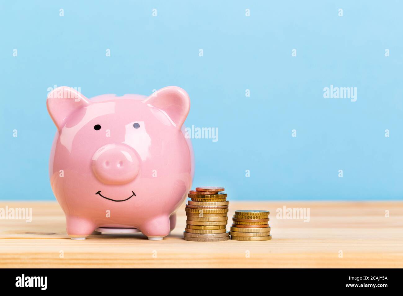 Pink piggy bank on wooden table and blue background. The concept of ...