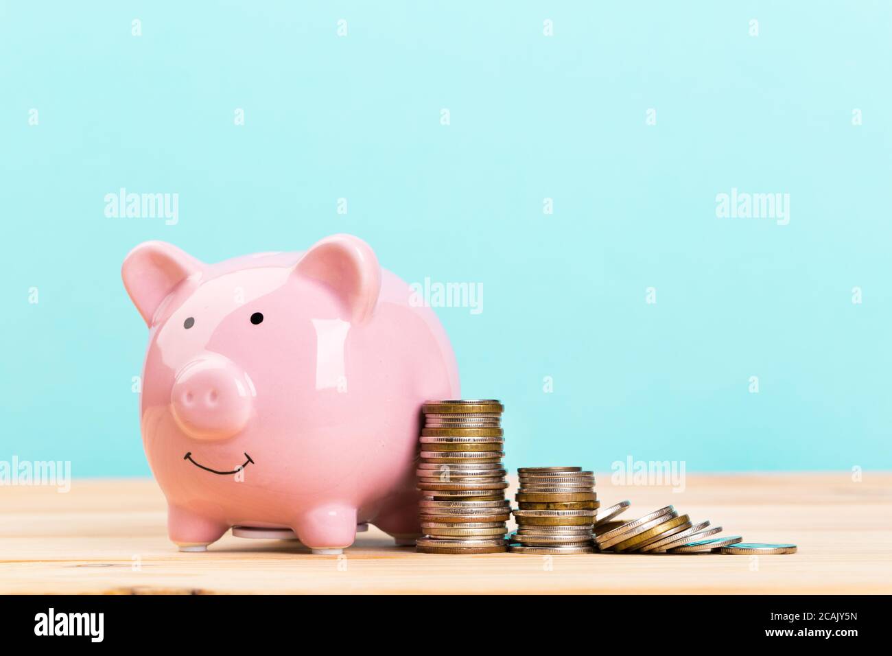 Pink piggy bank on wooden table and blue background. The concept of ...