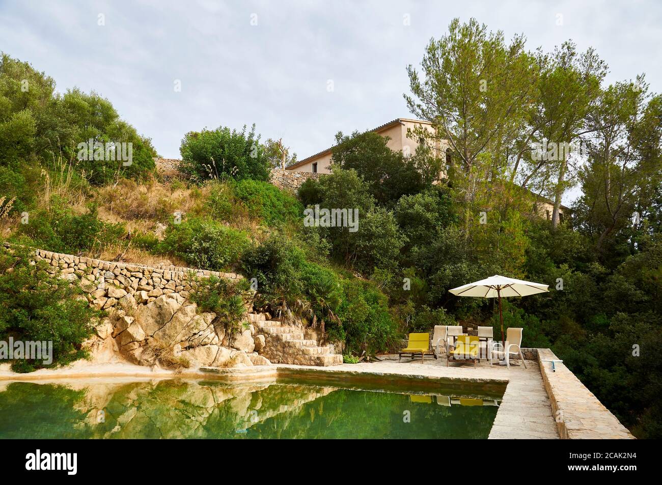 Natural water outdoor swimming pool with hammocks and sun umbrella at a property in Serra de Tramuntana (Andratx, Majorca, Balearic Islands, Spain) Stock Photo