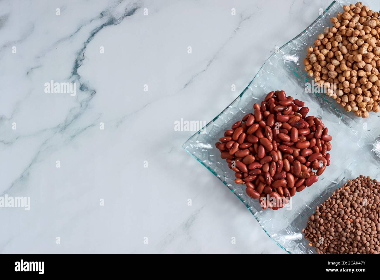 Top view of red kidney beans, brown lentils, and chickpeas in four
