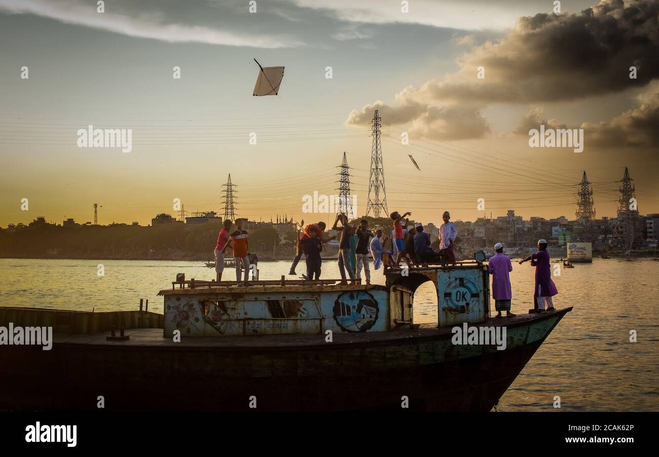 Children are enjoying on boat . They are local children . I captured this image from Burigongga river, Dhaka, Bangladesh . They are enjoying with kite Stock Photo