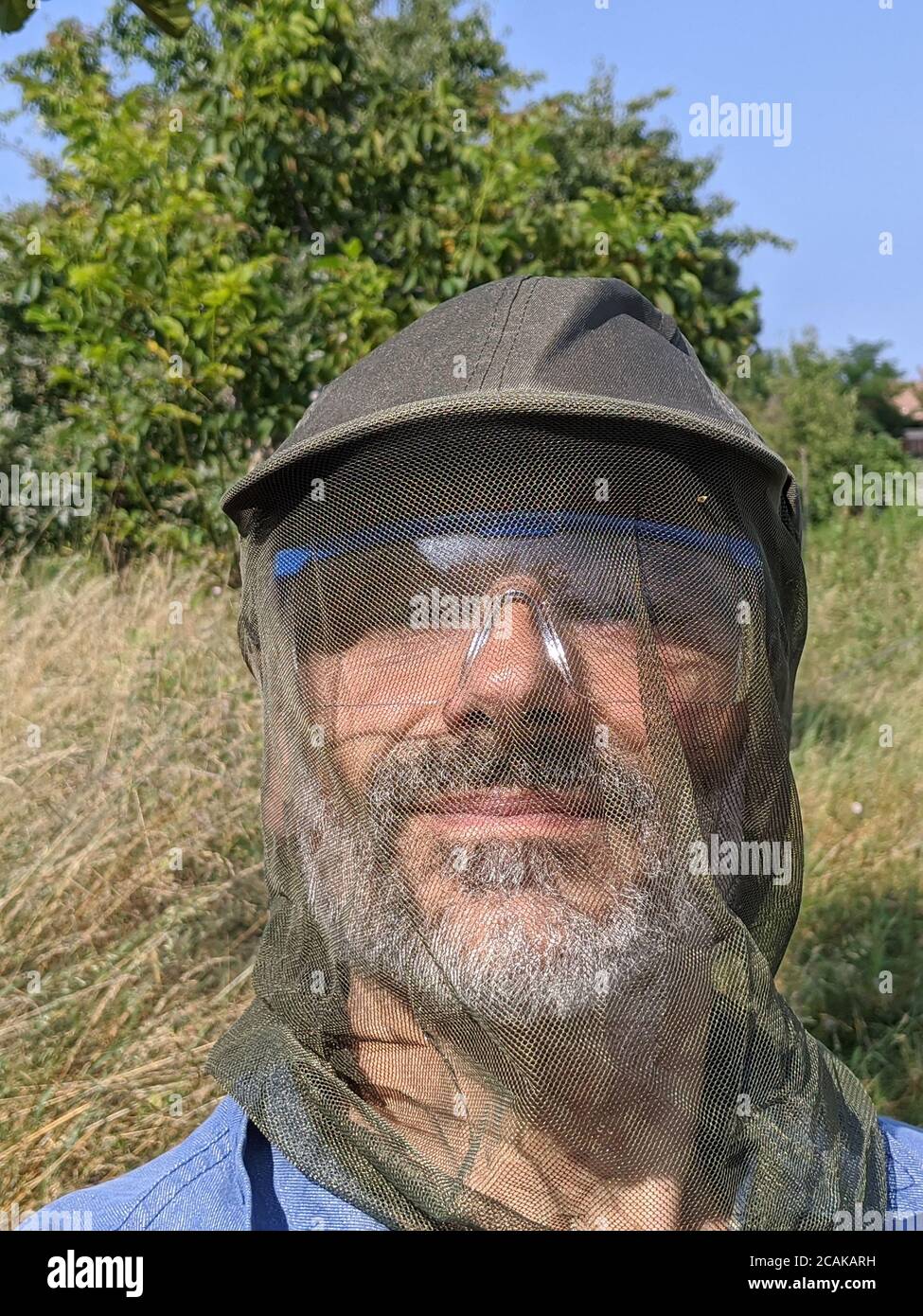 Mature caucasian man wearing anti mosquito cap Stock Photo