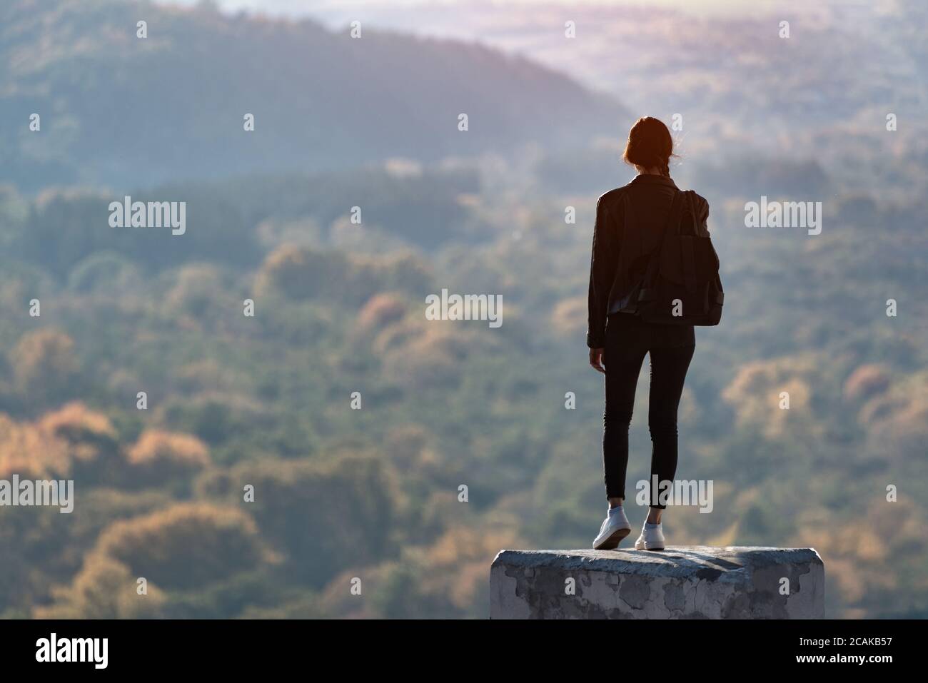 Girl stands on a hill and looks into the distance of the forest. Back ...