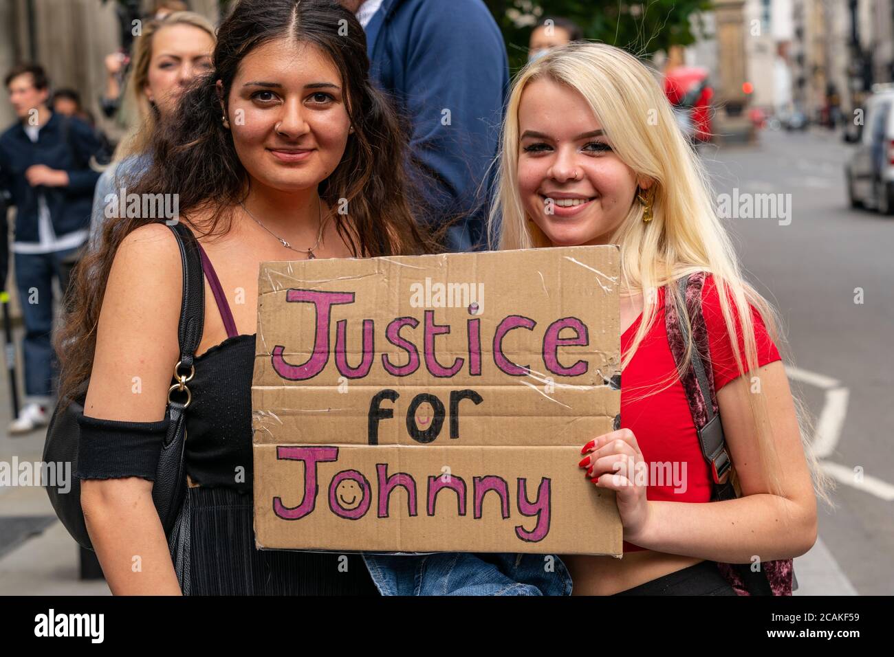 LONDON, ENGLAND - JULY 28, 2020: Beautiful female supporters holding a banner for Johnny Depp fan outside the High Court in London during his Court ca Stock Photo