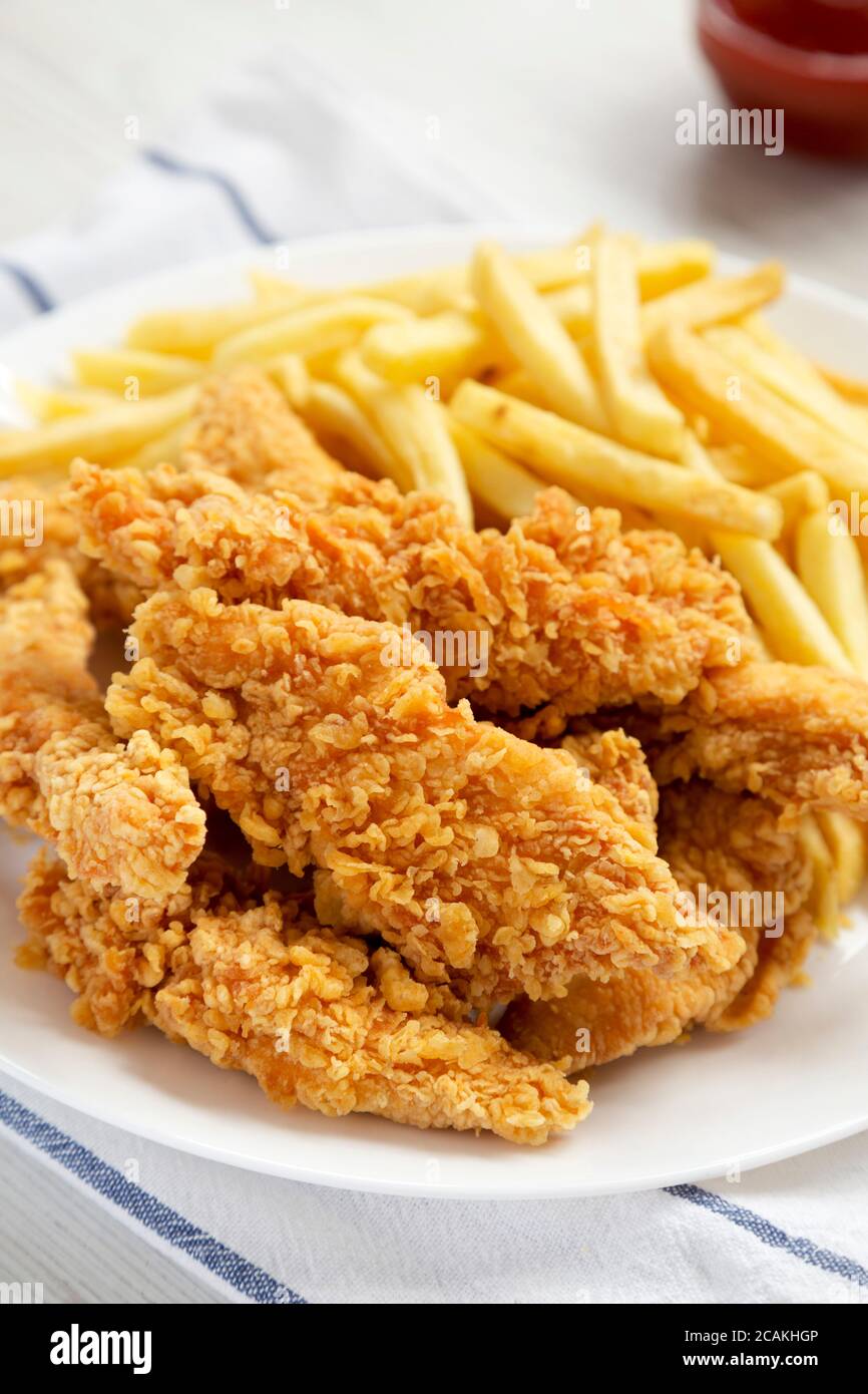 Homemade Crispy Chicken Tenders and French Fries on a white plate, side