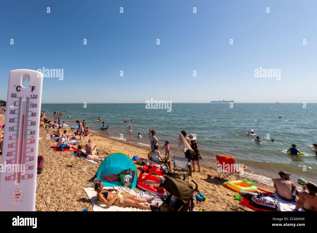 Busy beach on a hot day in Southend on Sea, Essex, UK during the COVID-19 Coronavirus pandemic. Thermometer showing high temperature Stock Photo