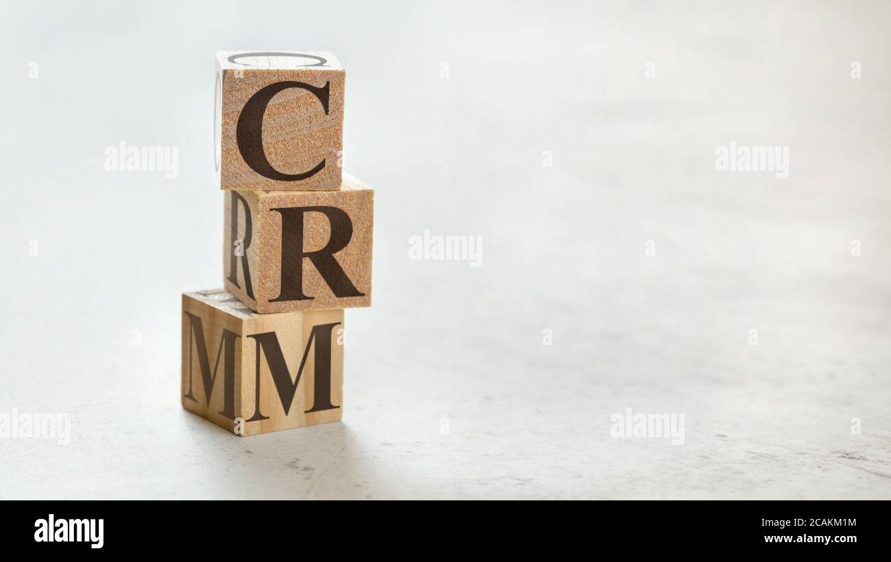 Pile with three wooden cubes - letters CRM meaning Customer relationship management on them, space for more text / images at right side. Stock Photo
