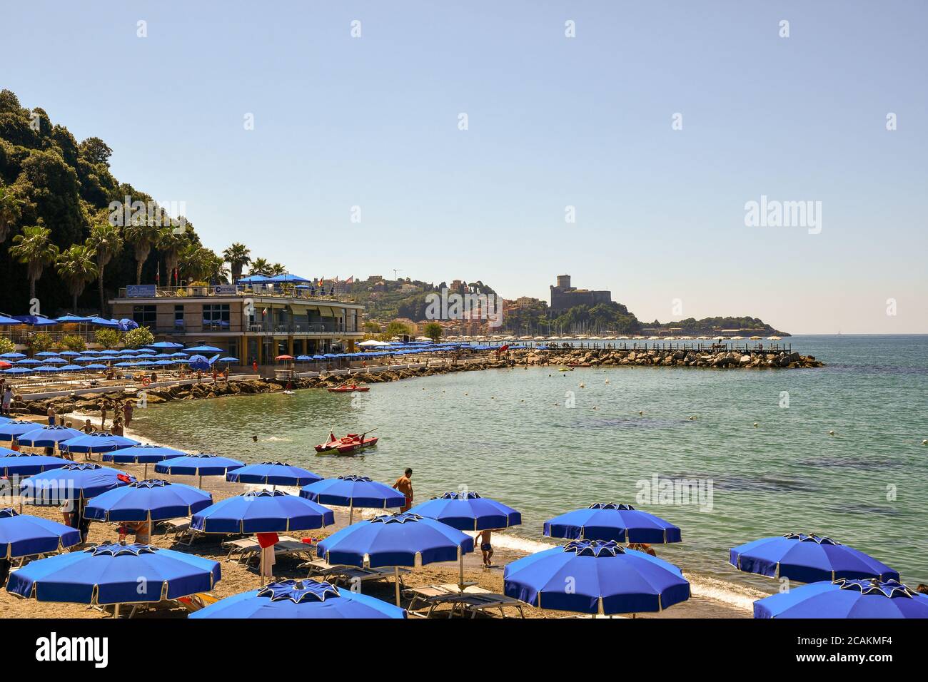 Scenic view of the bay with rows of sun umbrellas on the sandy beach and the old fishing village of Lerici in the background in summer, Liguria, Italy Stock Photo