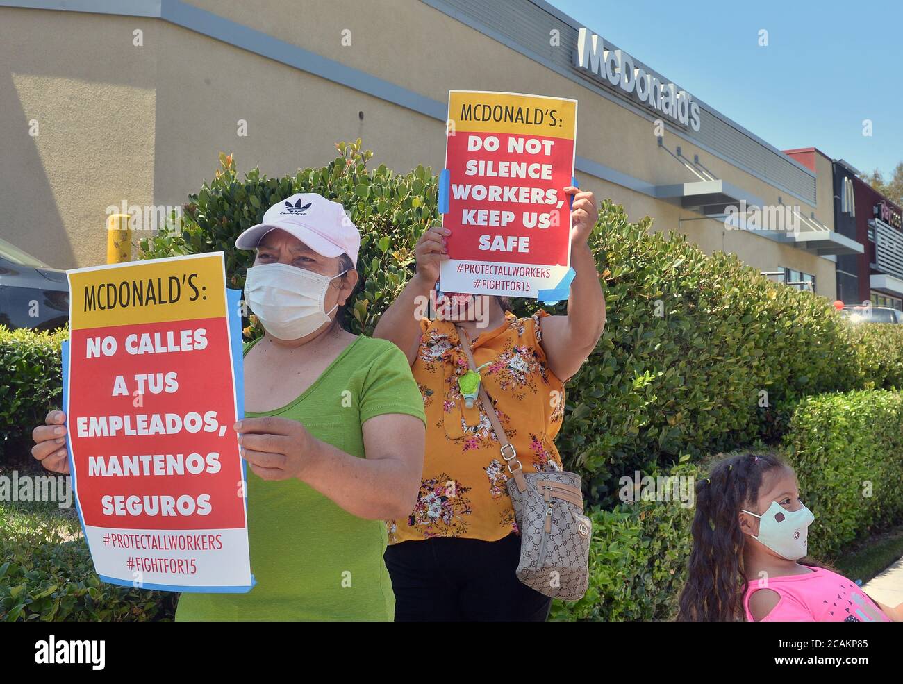 Women hold signs as McDonald's workers and their supporters protest what they allege is McDonald's attempts to silence a worker who spoke out about unsafe conditions amid the COVID-19 pandemic outside a McDonald's in Los Angeles on Friday, August 7, 2020. According to the protestors, the worker, Lizett Aguilar had filed multiple complaints with the county health department alleging an array of violations in her workplace including customers being served without masks, a lack of proper PPE and insufficient social distancing. At least five employees at the Marengo Street McDonald's where Aguilar Stock Photo