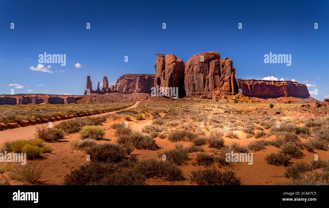 The Three Sisters and Mitchell Mesa, a few of the many massive Red Sandstone Buttes and Mesas in Monument Valley, Utah, United States Stock Photo