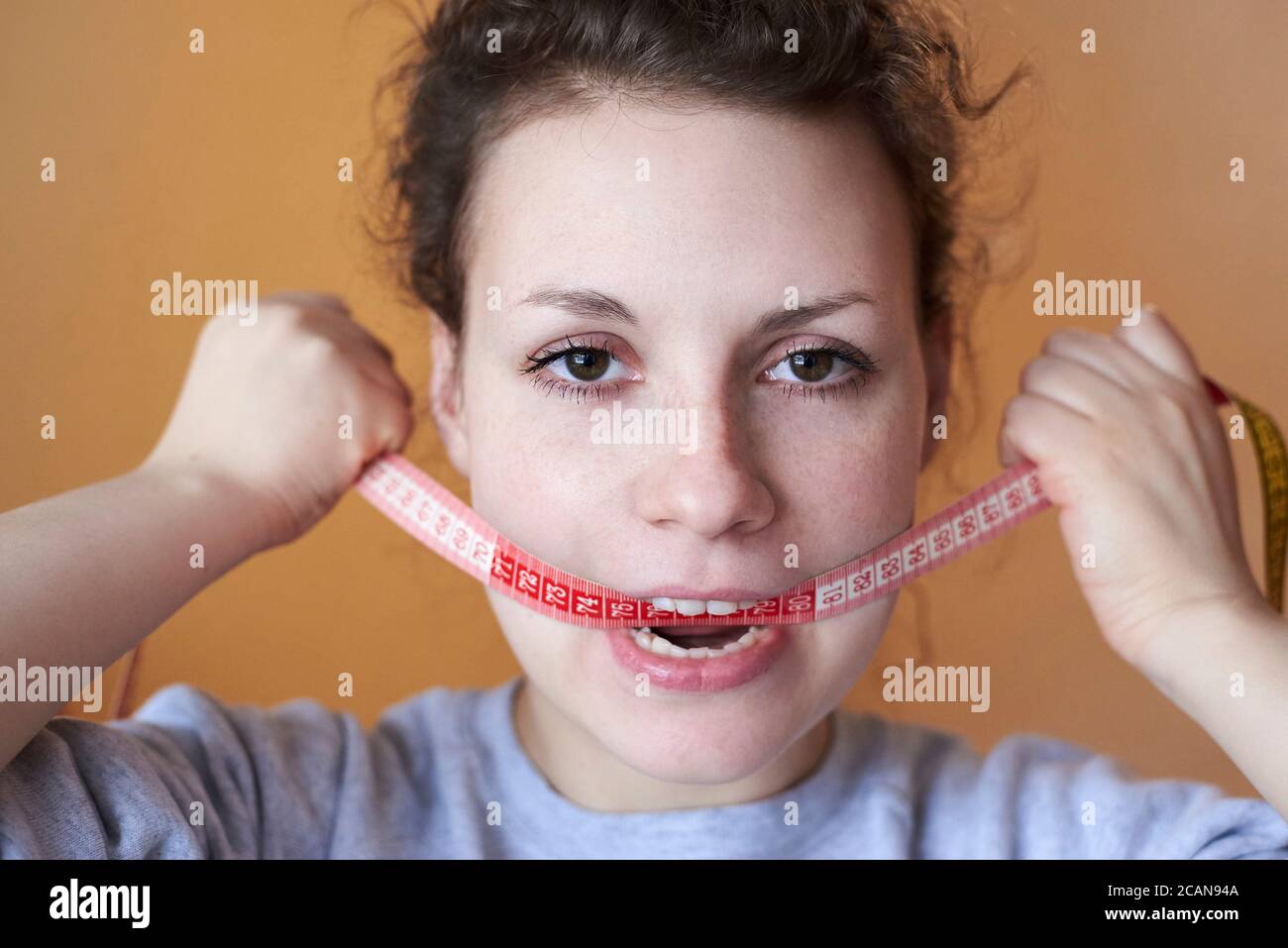 Sad woman with meter in the mouth, topic of losing excess weight, diet and stress. Stock Photo